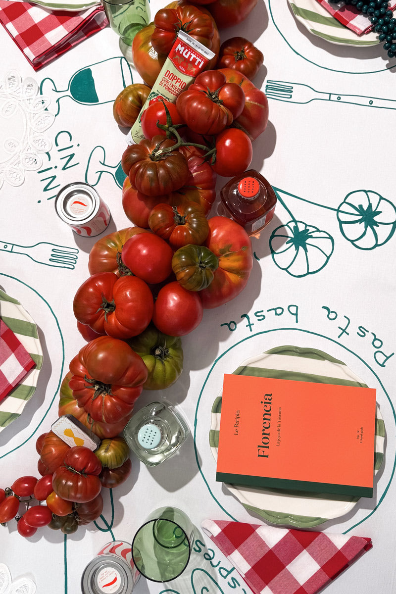 Mesa decorada con tomates y mantel ilustrado la temática de la guía de Florencia, con las guías impresas de Le Periplo y Match Tonic Water, tónicas de sabores.