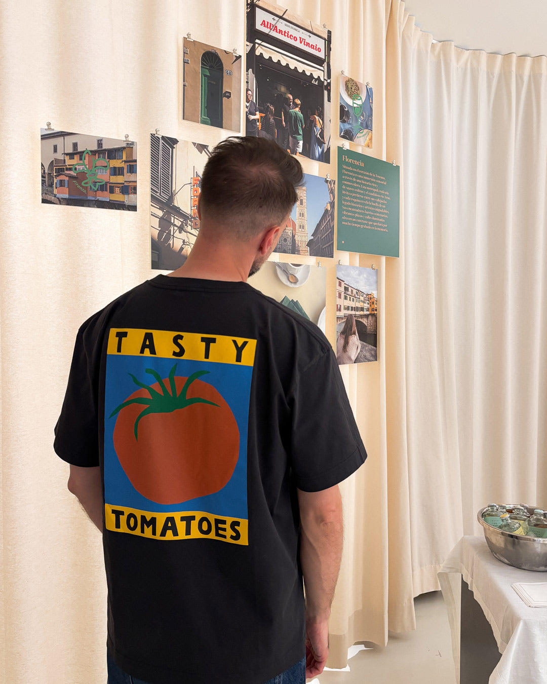 Espacio de Rughara Haus con la instalación visual de Le Periplo, asistente observando instalación con una camiseta llamativa de un tomate.