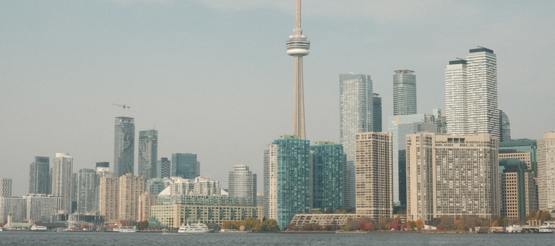 Vista panorámica del skyline de Toronto al atardecer, con la CN Tower destacando sobre la ciudad. Imagen de portada de la Guía de viaje urbana de Toronto de Le Periplo, con recomendaciones locales, lugares culturales y consejos para recorrer la ciudad por distritos.