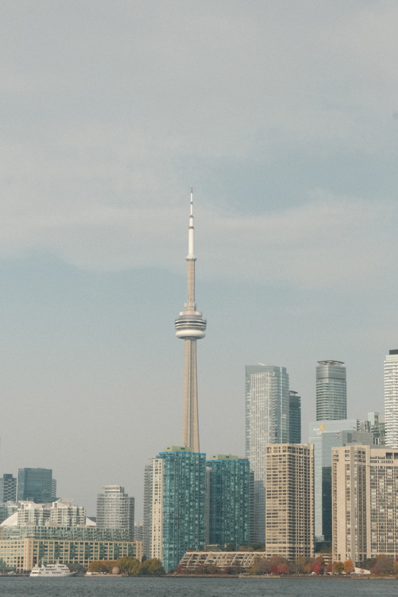 Vista panorámica del skyline de Toronto al atardecer, con la CN Tower destacando sobre la ciudad. Imagen de portada de la Guía de viaje urbana de Toronto de Le Periplo, con recomendaciones locales, lugares culturales y consejos para recorrer la ciudad por distritos.