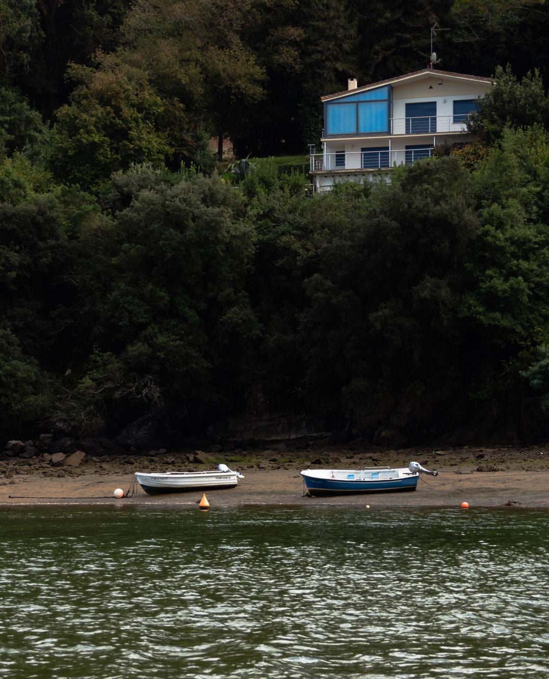 Vistas navegando desde el estuario, barcas, casas entre montaña y vegetación.