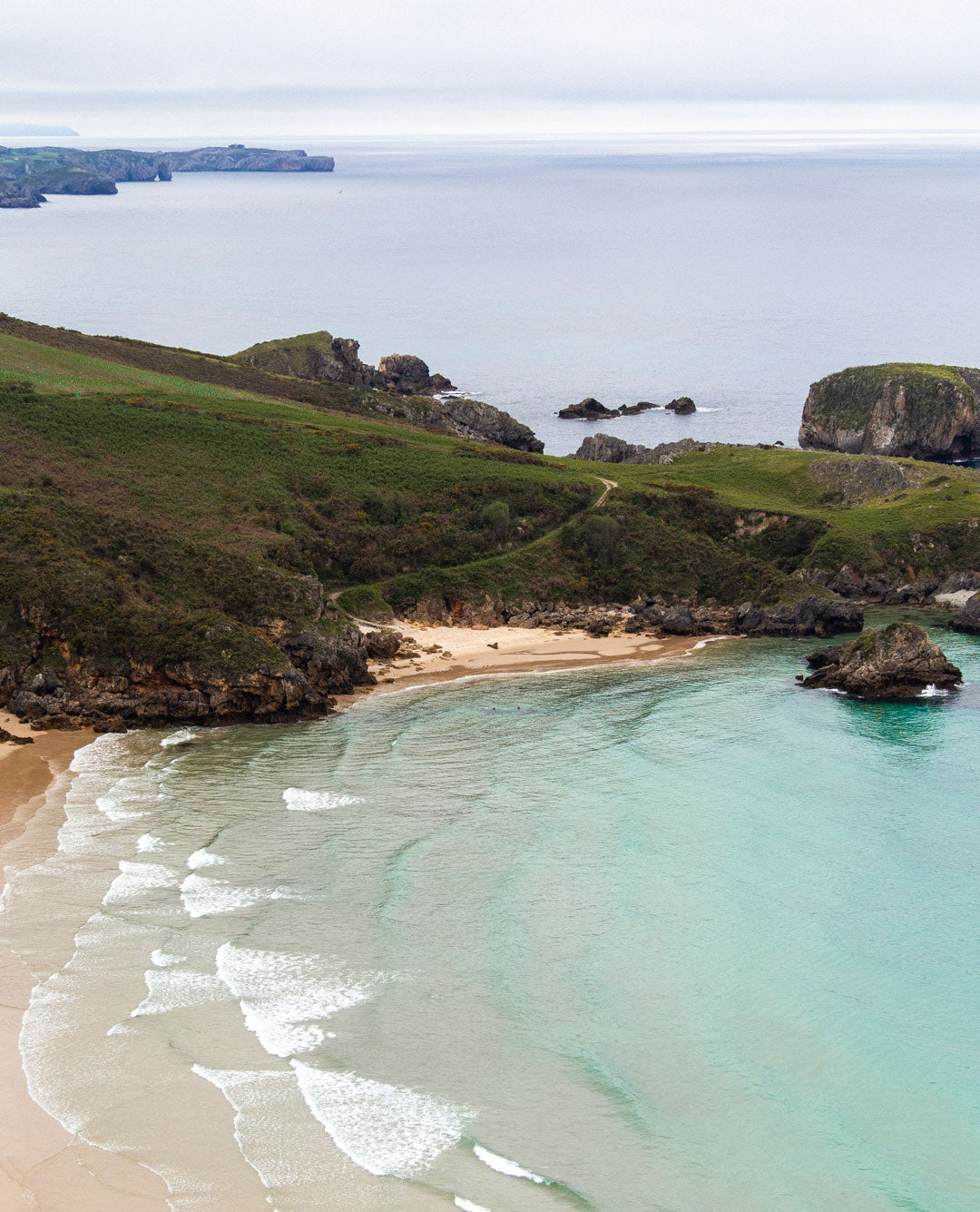 Vista aérea de un acantilado verde sobre el Cantábrico en la costa asturiana.